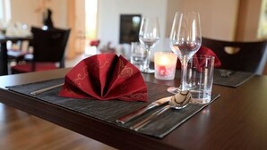 Una mesa de comedor dispuesta con servilleta roja, copas de vino y cubiertos.
