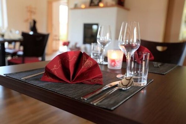 A dining table set with a red napkin, wine glasses, and cutlery.