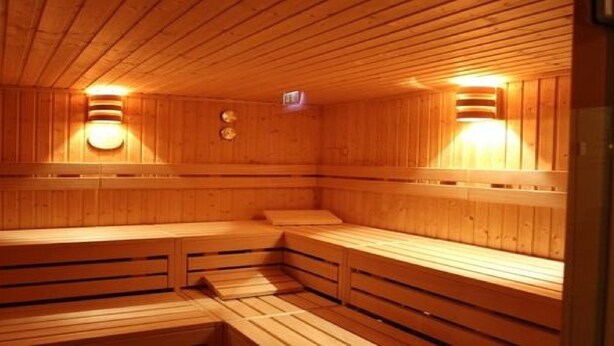 Una sauna de madera con bancos y luces en la pared.