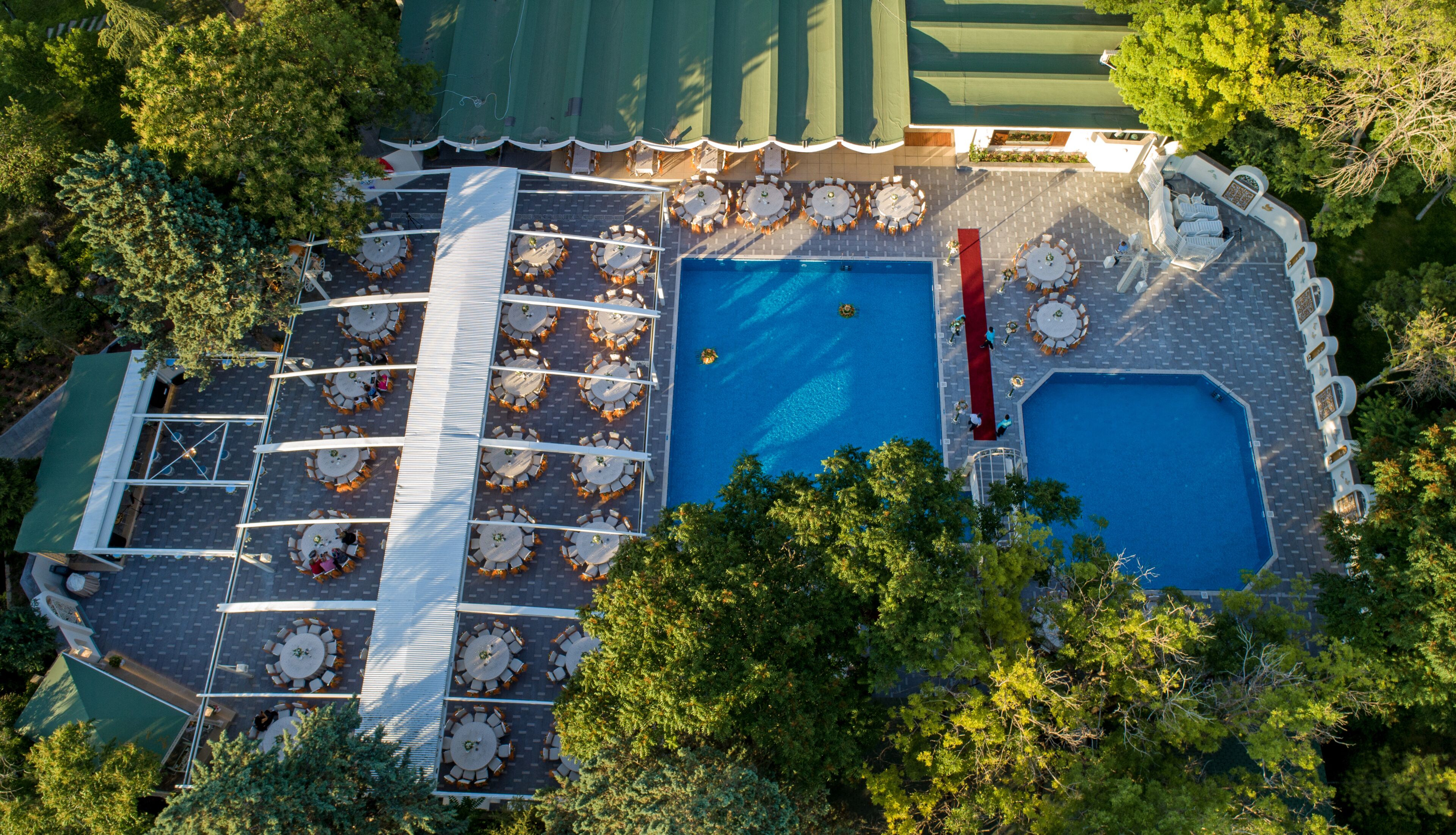 Vista aérea de una zona de piscina en la azotea, con varios sillones de sol y una piscina central.