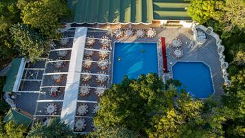 Vista aérea de una zona de piscina en la azotea, con varios sillones de sol y una piscina central.