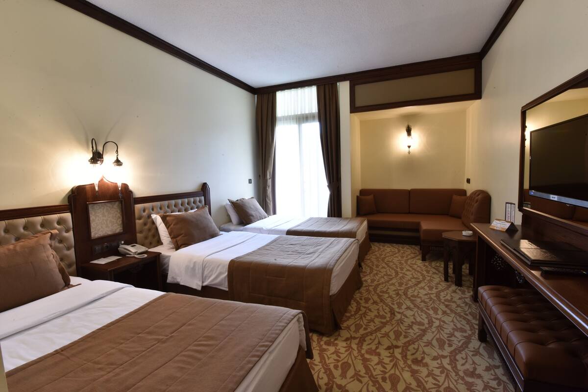 Una habitación de hotel con dos camas, un sofá, un televisor y un escritorio.
