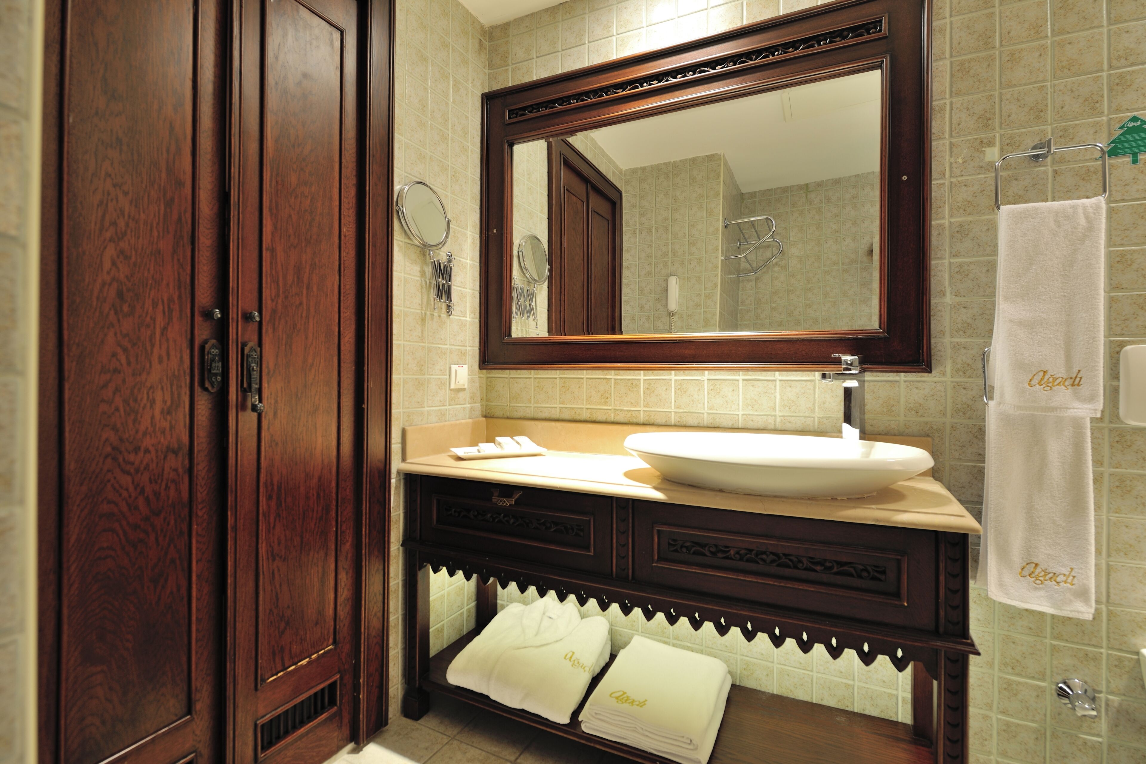 A bathroom with a large mirror, wooden cabinets, a sink, and a towel rack.