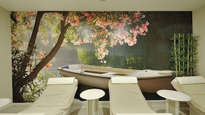 A spa room with a mural of a boat on water, two reclining chairs, and a small table. - Agacli Hotel (Aksaray)