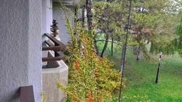 Un balcón con vistas a un jardín y árboles.