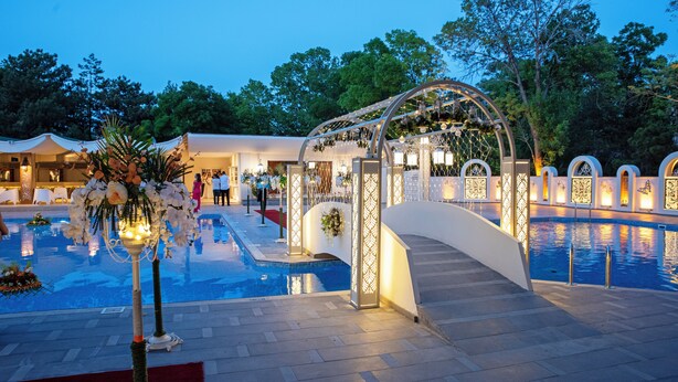 A pool area with a decorative archway, a clear pool, and surrounding greenery. - Agacli Hotel (Aksaray)