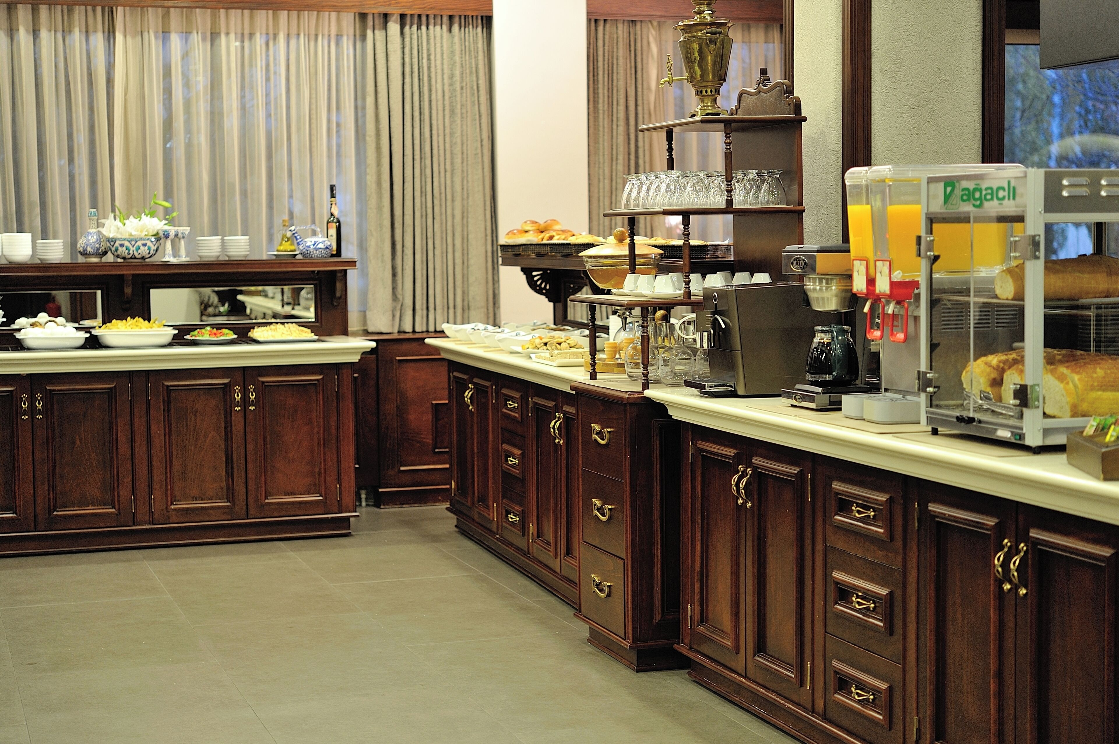 A buffet setup with various food items, a coffee machine, and a juice dispenser.