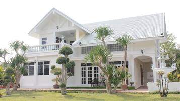 Stunning hotel with spacious balconies, large windows, and a covered entrance, set amidst beautifully landscaped gardens.