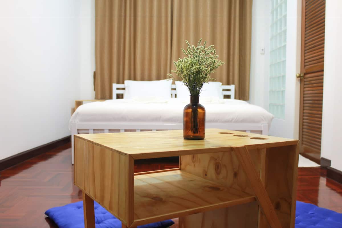 Un pupitre de madera con un florero de flores en una habitación con cama y cortinas.