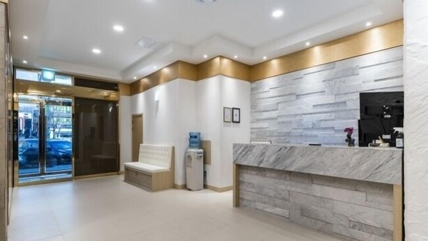 A hotel reception area with a marble counter, a bench, and a water dispenser. - Central Tourist Hotel (Anyang)