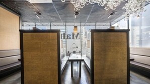 A modern, minimalist conference room with a glass partition, a long table, and two high stools. - Central Tourist Hotel (Anyang)