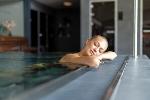 A person relaxing in a modern indoor swimming pool with clear glass walls. - Starby Spa, Hotell & Konferens (Vadstena)