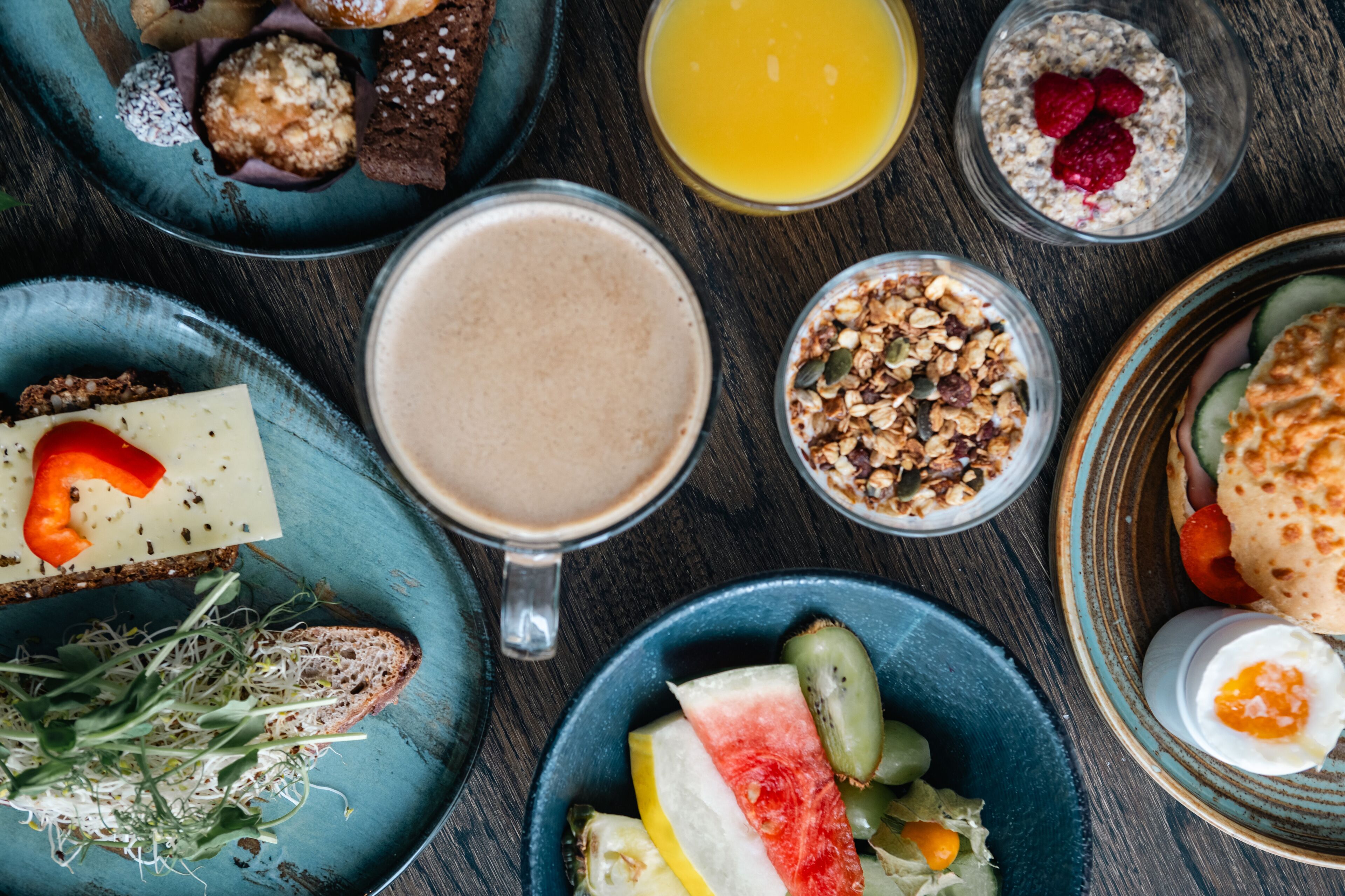 Ett urval av frukosträtter, inklusive rostat bröd, frukt, yoghurt och en varm dryck.