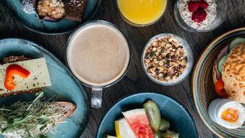 Ett urval av frukosträtter, inklusive rostat bröd, frukt, yoghurt och en varm dryck.