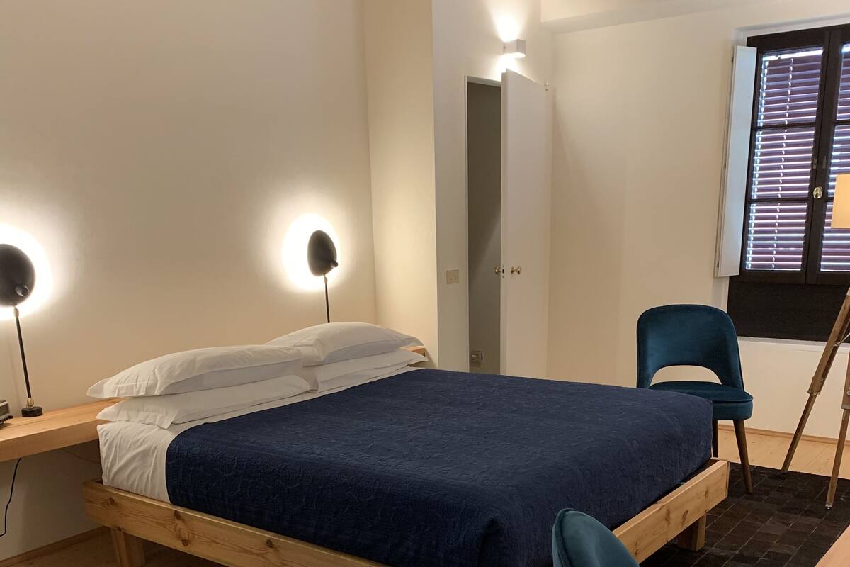 Un dormitorio con una cama de madera, un escritorio con silla y una ventana con persianas.