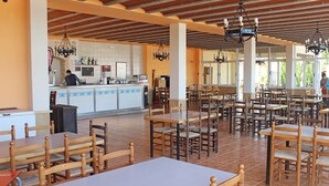 Ein geräumiger Essbereich mit Holztischen und -stühlen, eine Bar mit Theke sowie ein Fliesenboden.