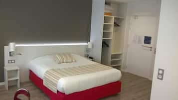 A bedroom with a bed, bedside tables, a wardrobe, and a door.