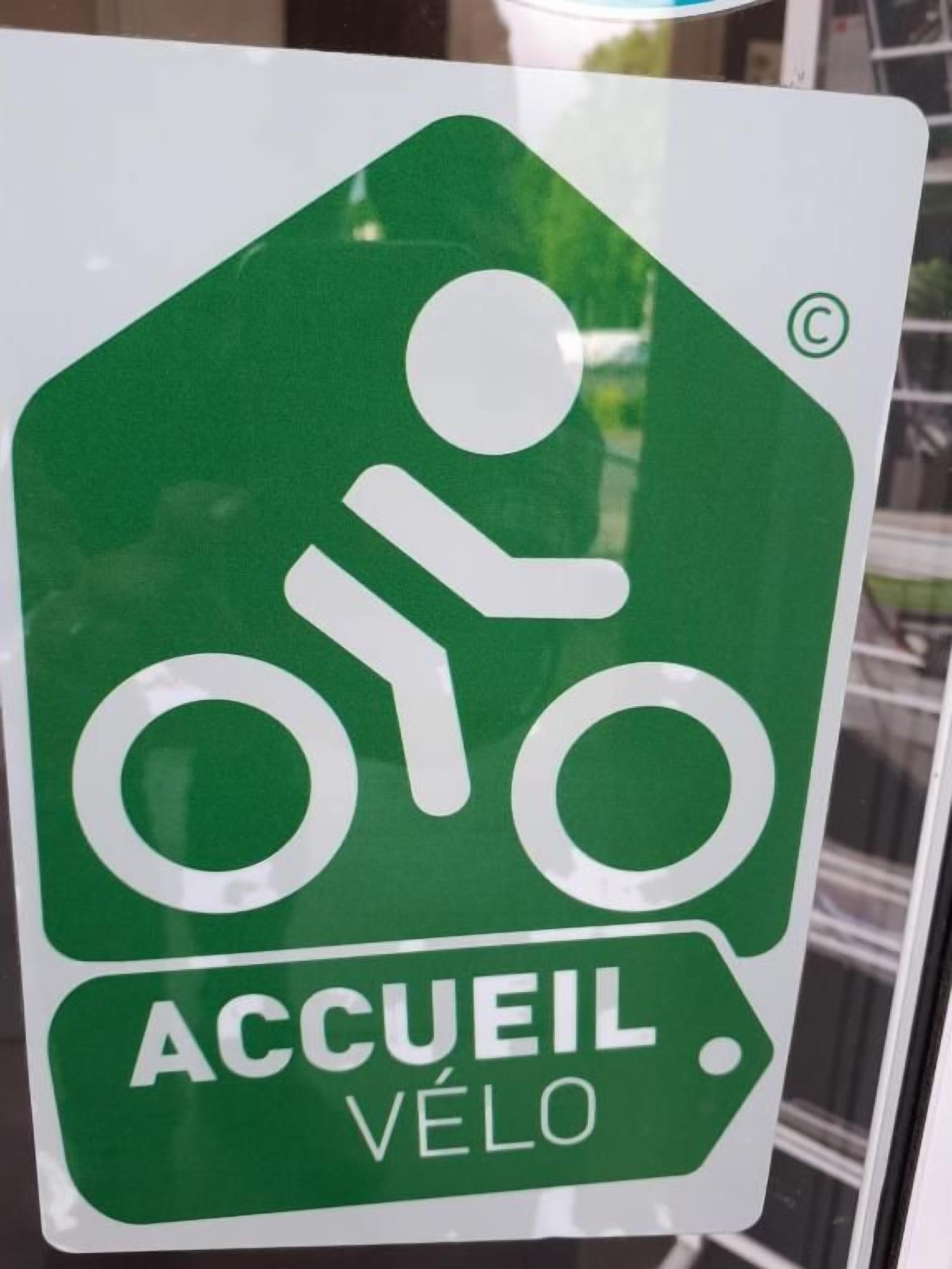 A green sign with a white bicycle symbol and the text 'ACCUEIL VÉLO' indicating a bicycle parking area.