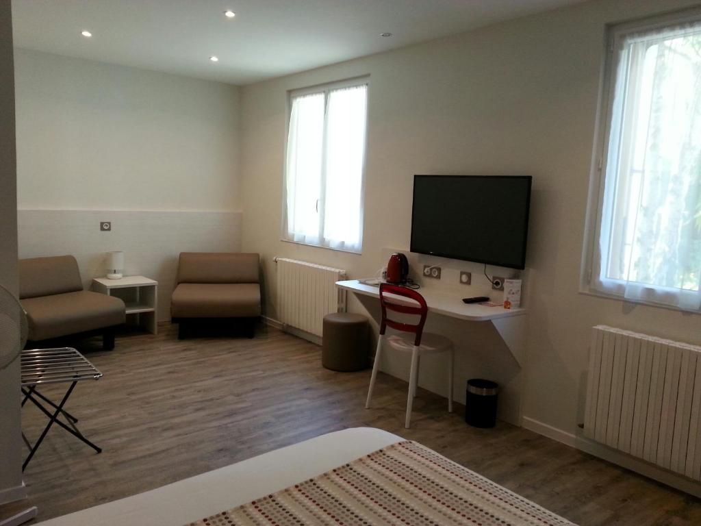 Een moderne woonkamer met een bank, een bureau met een computer, een televisie en een raam.