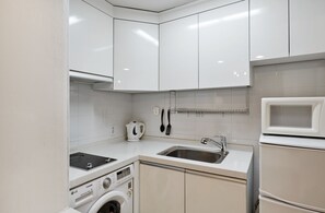 Eine moderne Küche mit weißen Schränken, einer eingebauten Mikrowelle, einem Spülbecken und einer Waschmaschine.