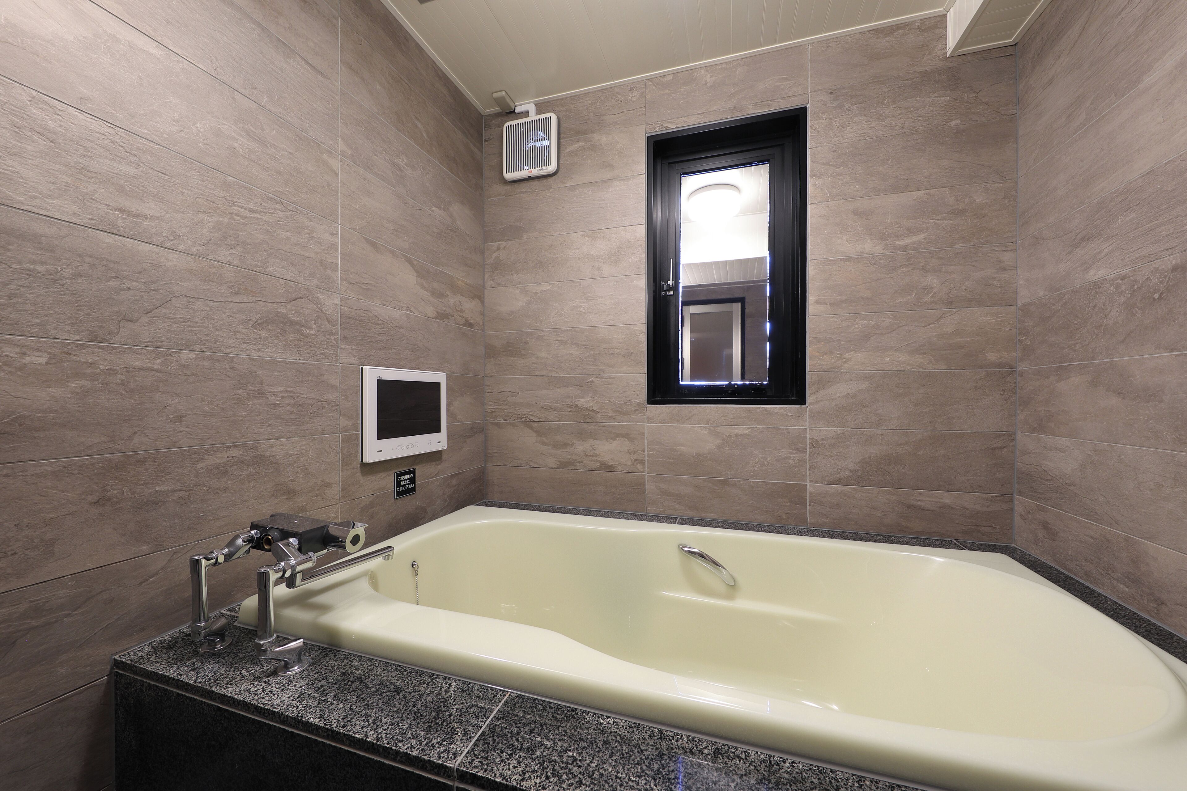 Une salle de bain avec une baignoire sur pieds, un lavabo encastré et une petite fenêtre.