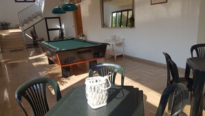 A pool table in a room with a staircase, chairs, and a window. - Villa Erry (Trani)