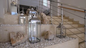 Una escalera con barandillas de metal, piedras blancas y faroles de cristal.
