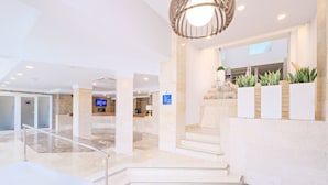 Un moderno vestíbulo de hotel con suelo de mármol, una escalera y un mostrador de recepción.