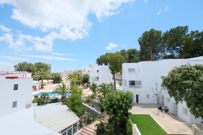 A courtyard with white buildings, a swimming pool, and palm trees. - Azuline Palmanova Gardens (Calvia)