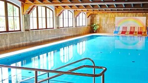 Ein Innenpool mit Holzterrasse, großen Fenstern und einem Wandgemälde mit Regenbogen.