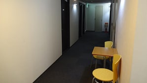 En smal gang med et træbord og to gule stole, en brandslukker og en dør med skilt nummer 403.