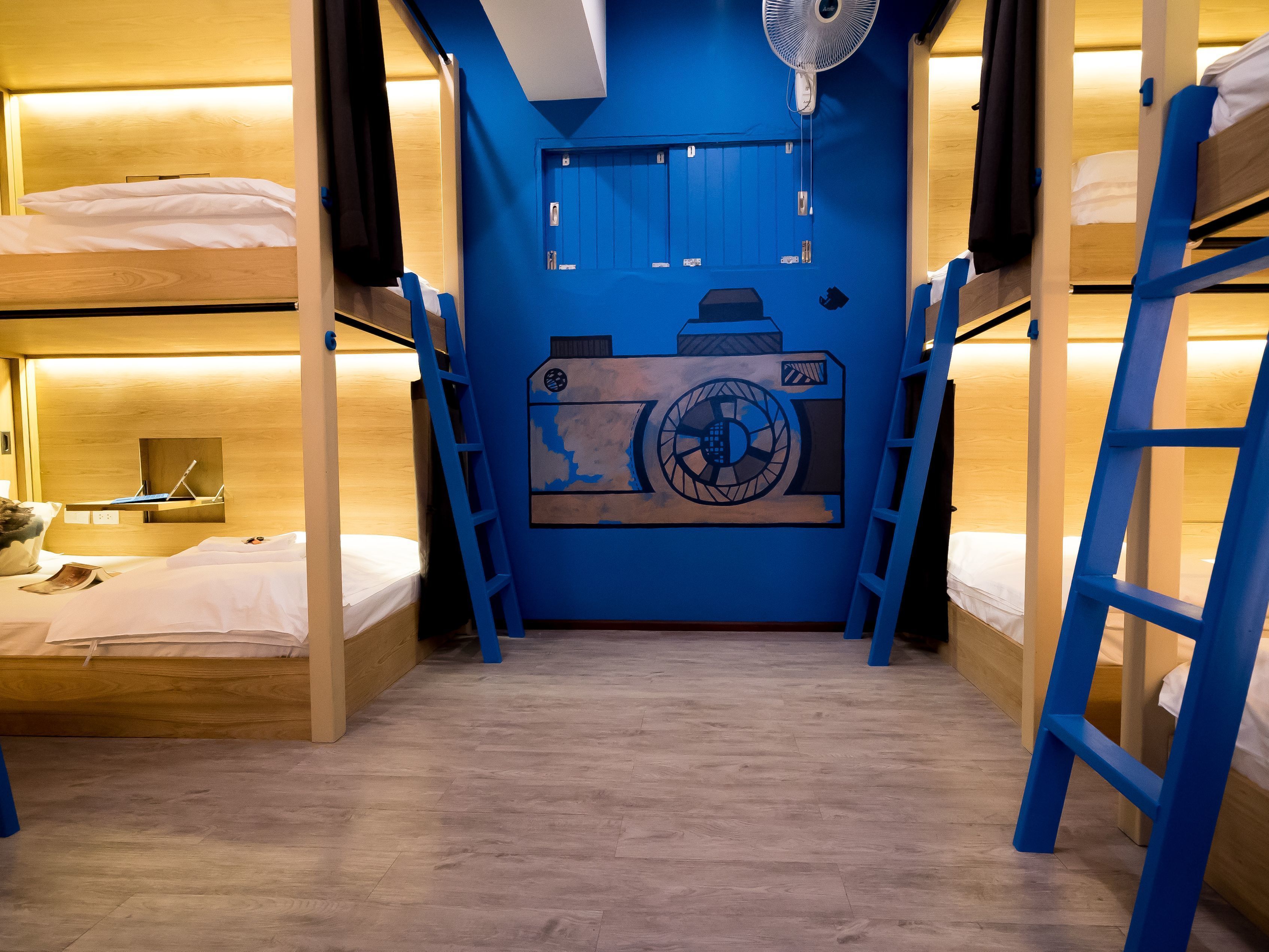 A bunk bed room with a blue wall and a fan above the door.
