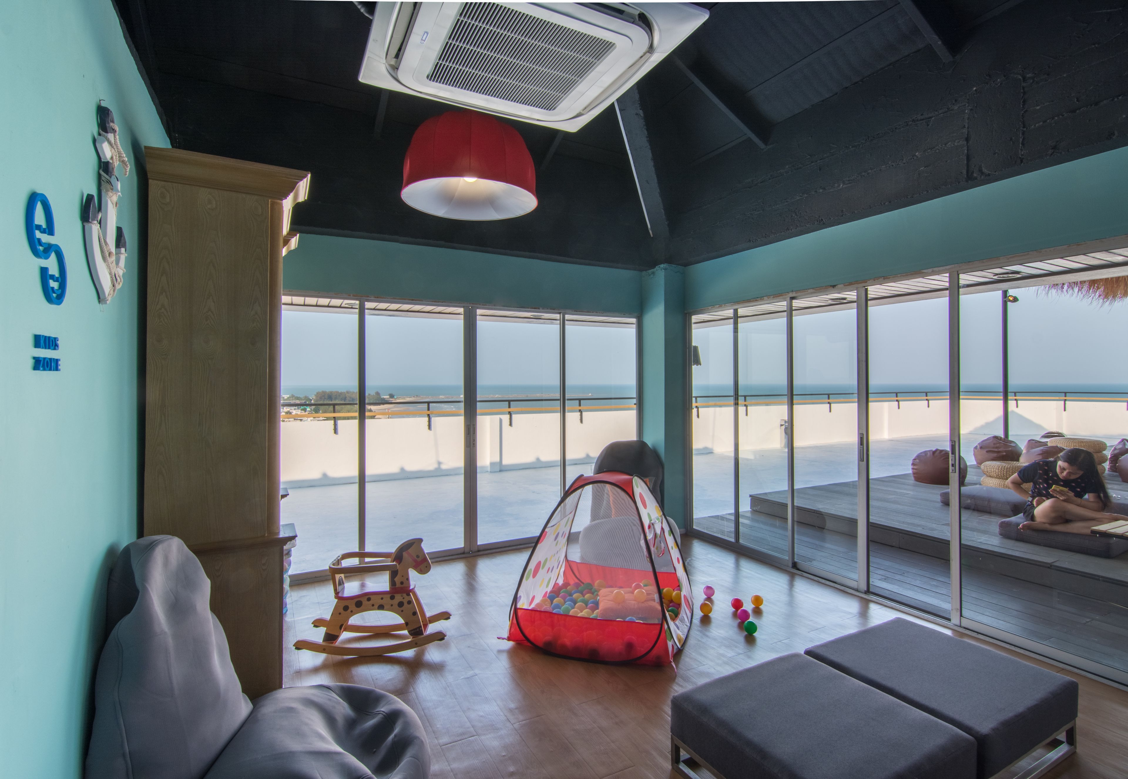 A room with a view of the beach, a rocking chair, a play tent, and a bench.