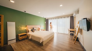 Una habitación de hotel moderna con una cama grande, una mesita de noche de madera, un escritorio y un televisor.