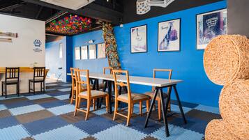 Una habitación con pared azul, una mesa de madera con sillas y un suelo a cuadros.