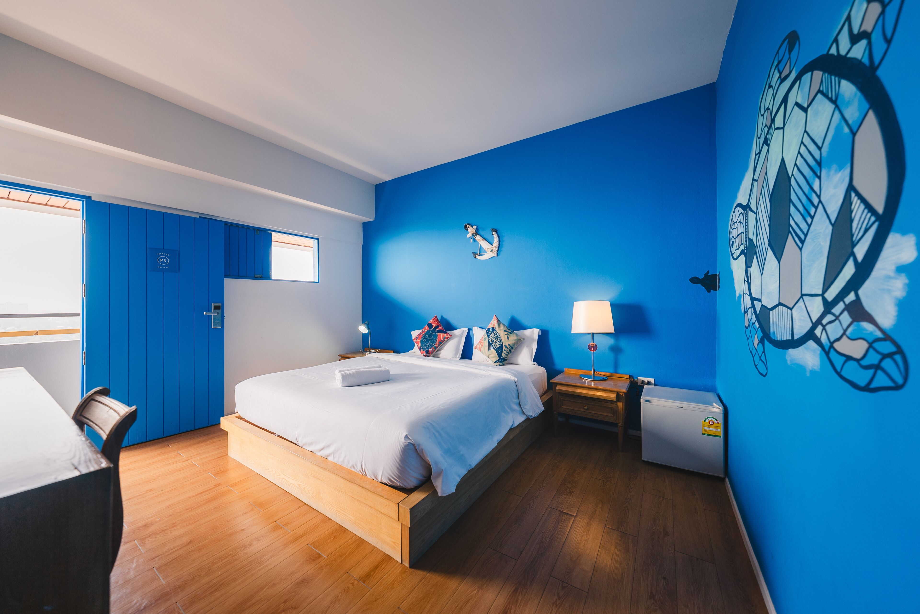 A modern bedroom with a large bed, a desk, and a wardrobe.