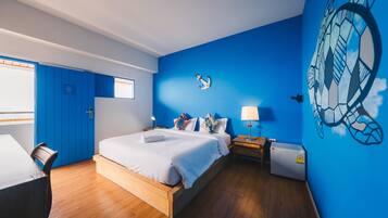 A modern bedroom with a large bed, a desk, and a wardrobe.