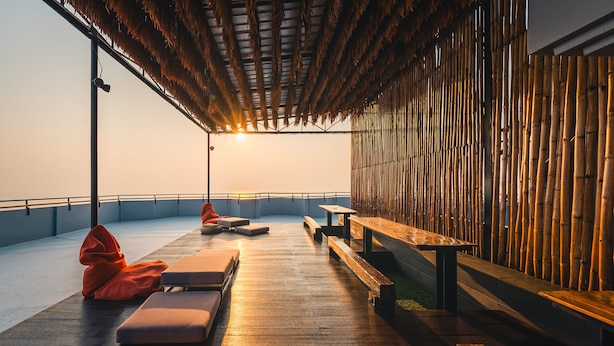 Una terraza de madera con bancos y sillones de descanso, con vistas a un cuerpo de agua.