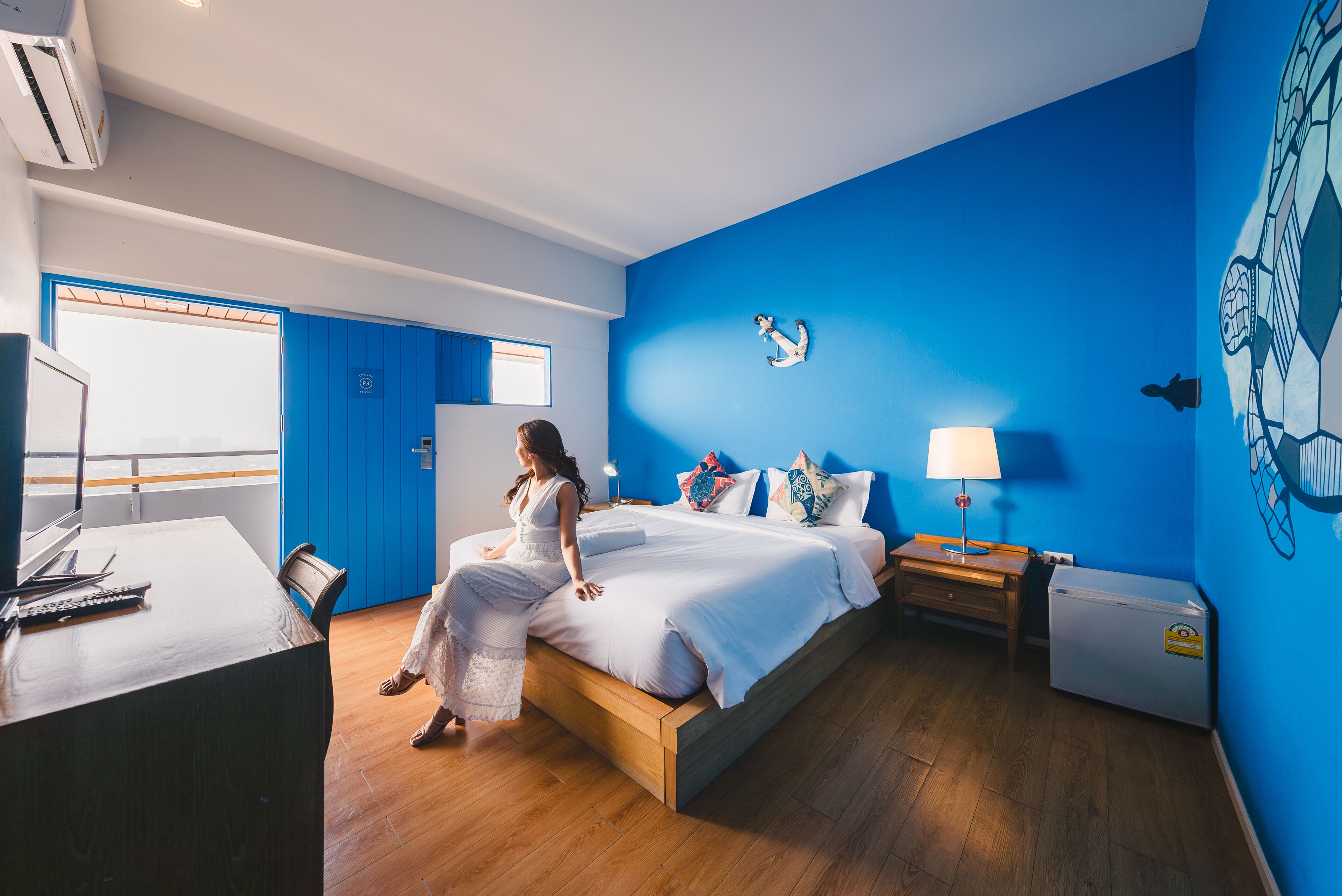 Una habitación con cama, escritorio, silla, lámpara y un adorno en la pared.