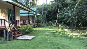 Une maison de style bungalow dotée d’un toit végétalisé, d’une terrasse en bois et d’un jardin bien entretenu avec un chemin en pierre.