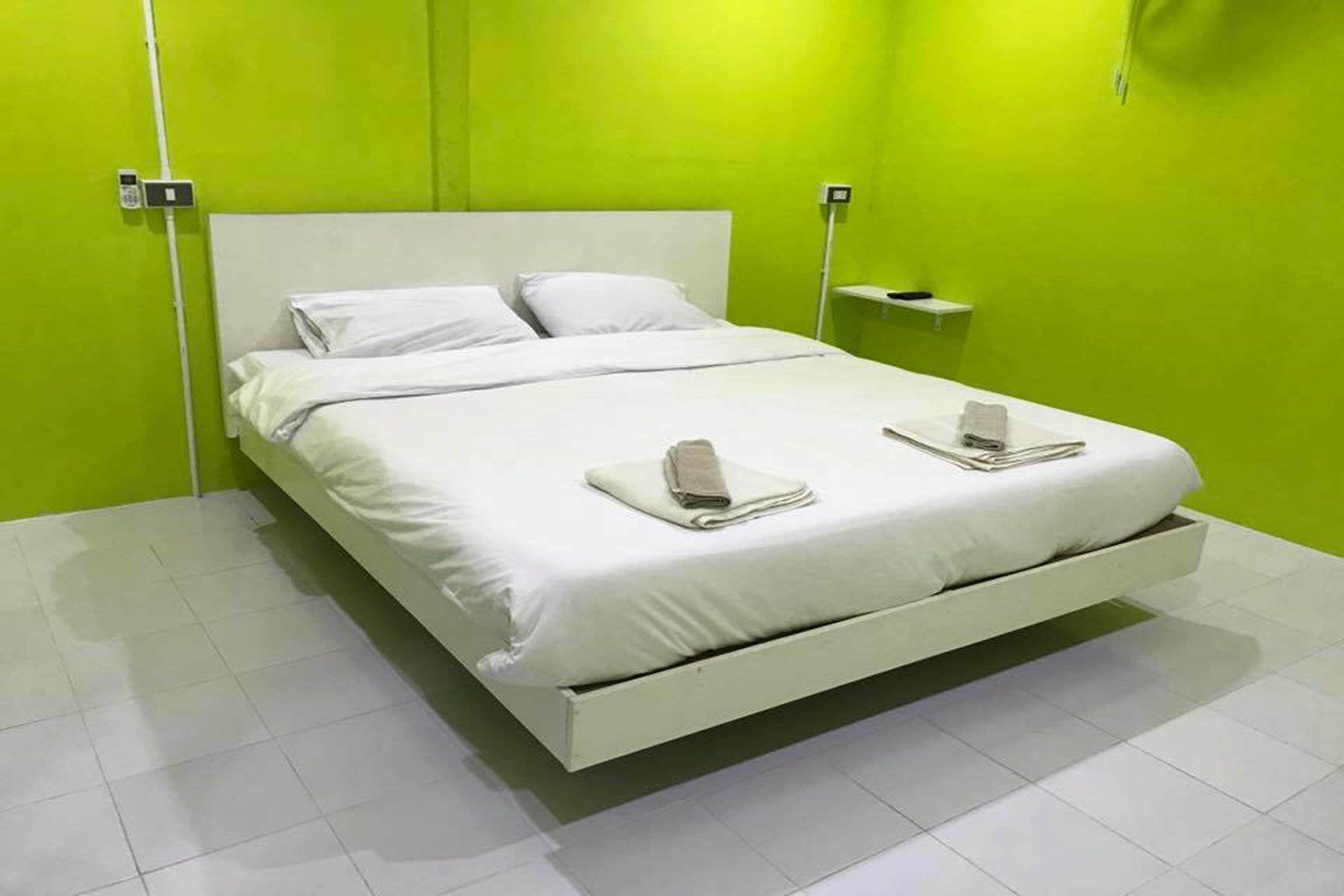 Una cama con ropa de cama blanca, dos toallas, una mesita de noche y una lámpara.