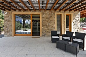 A covered outdoor area with stone walls, a glass door leading inside, and outdoor furniture. - Agriturismo Terra e Lago d'Iseo (Paratico)