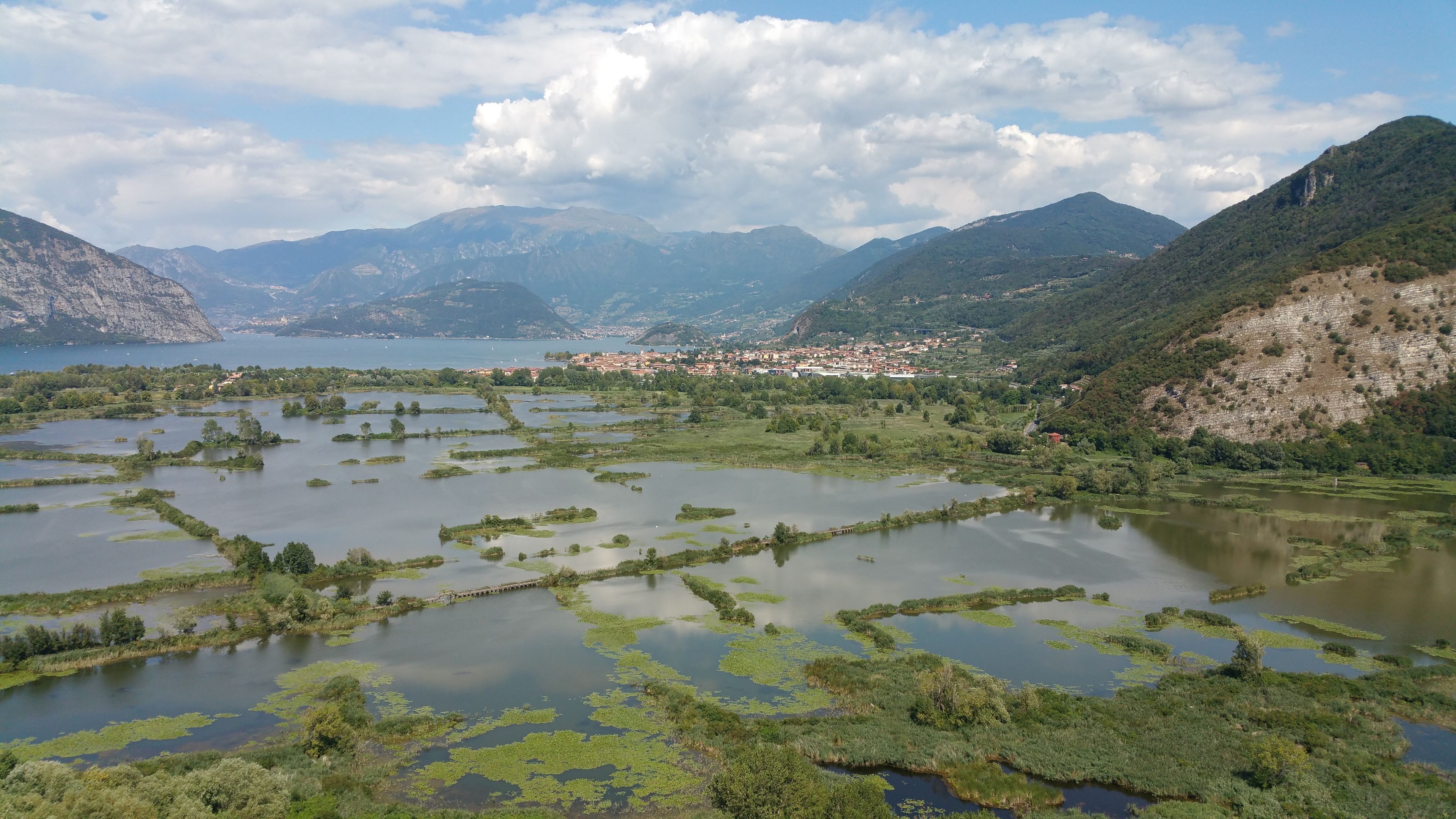 Ein Panoramablick auf einen See, umgeben von Bergen, mit einer kleinen Stadt in der Ferne.
