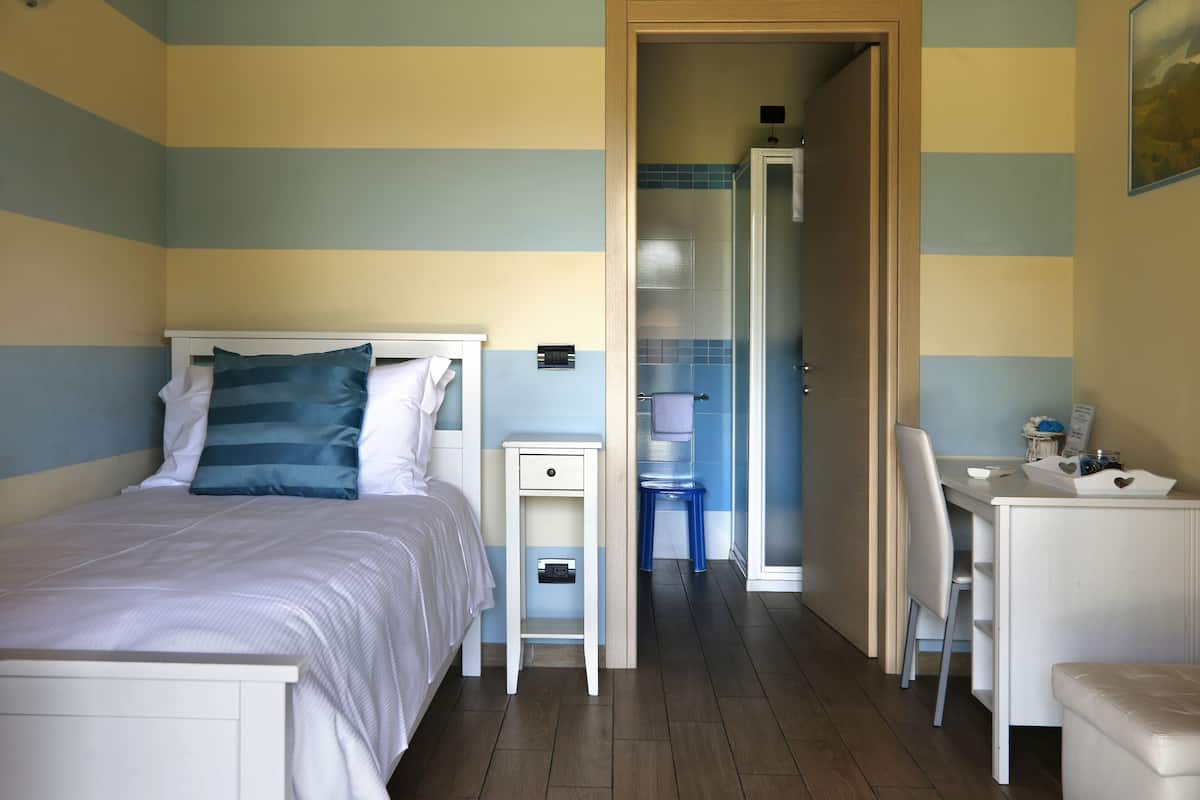Een slaapkamer met een bed, nachtkastje en bureau met stoel.
