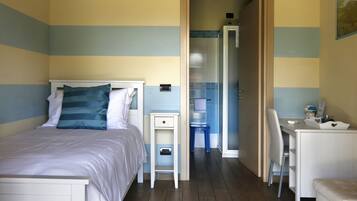 Un dormitorio con cama, mesita de noche y escritorio con silla.