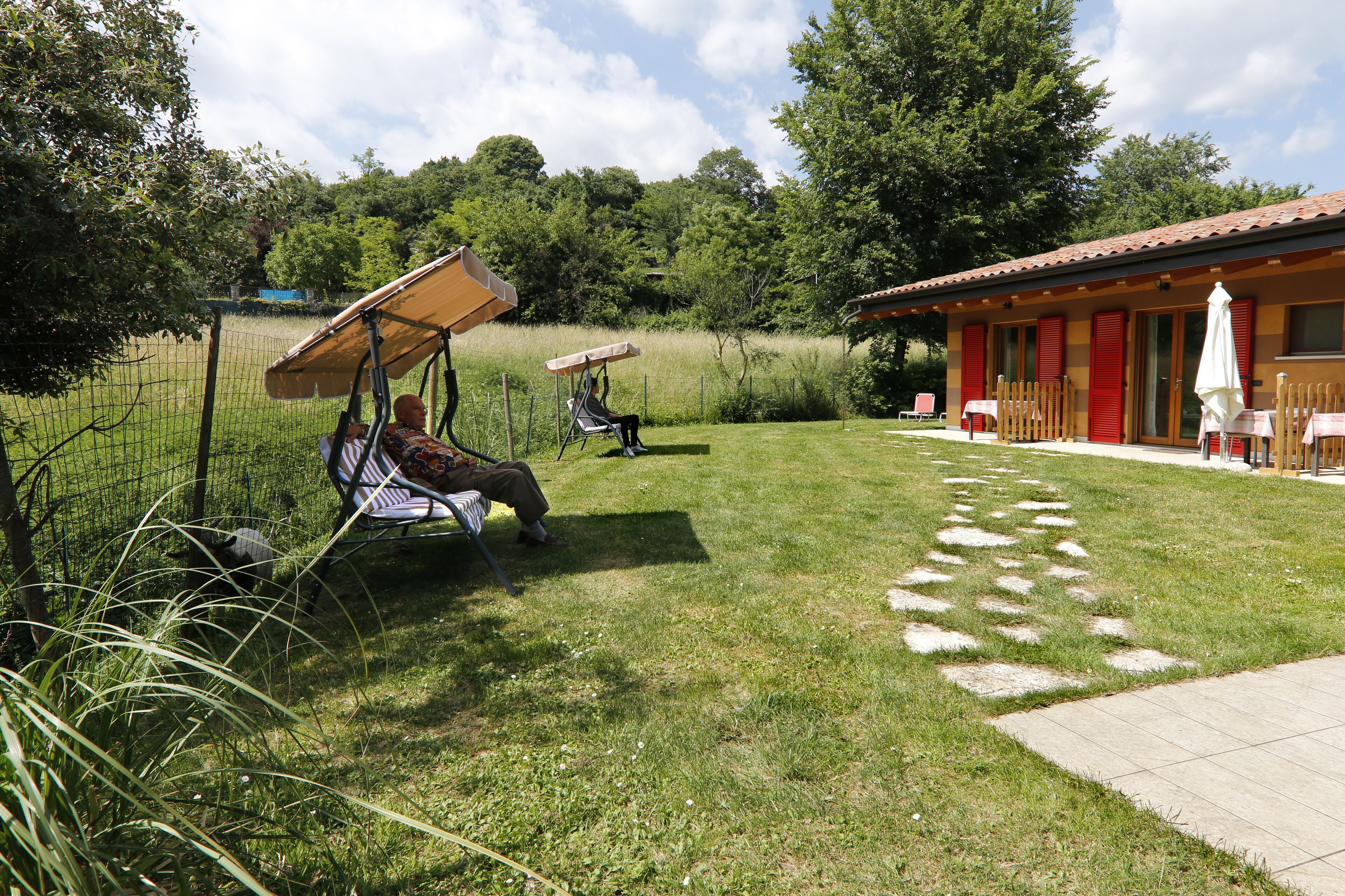 Een terras met buitenmeubels en een gebouw met rode luiken.