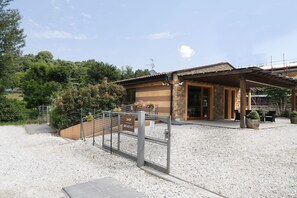 A building with a stone facade, a covered patio area, and a gravel driveway. - Agriturismo Terra e Lago d'Iseo (Paratico)