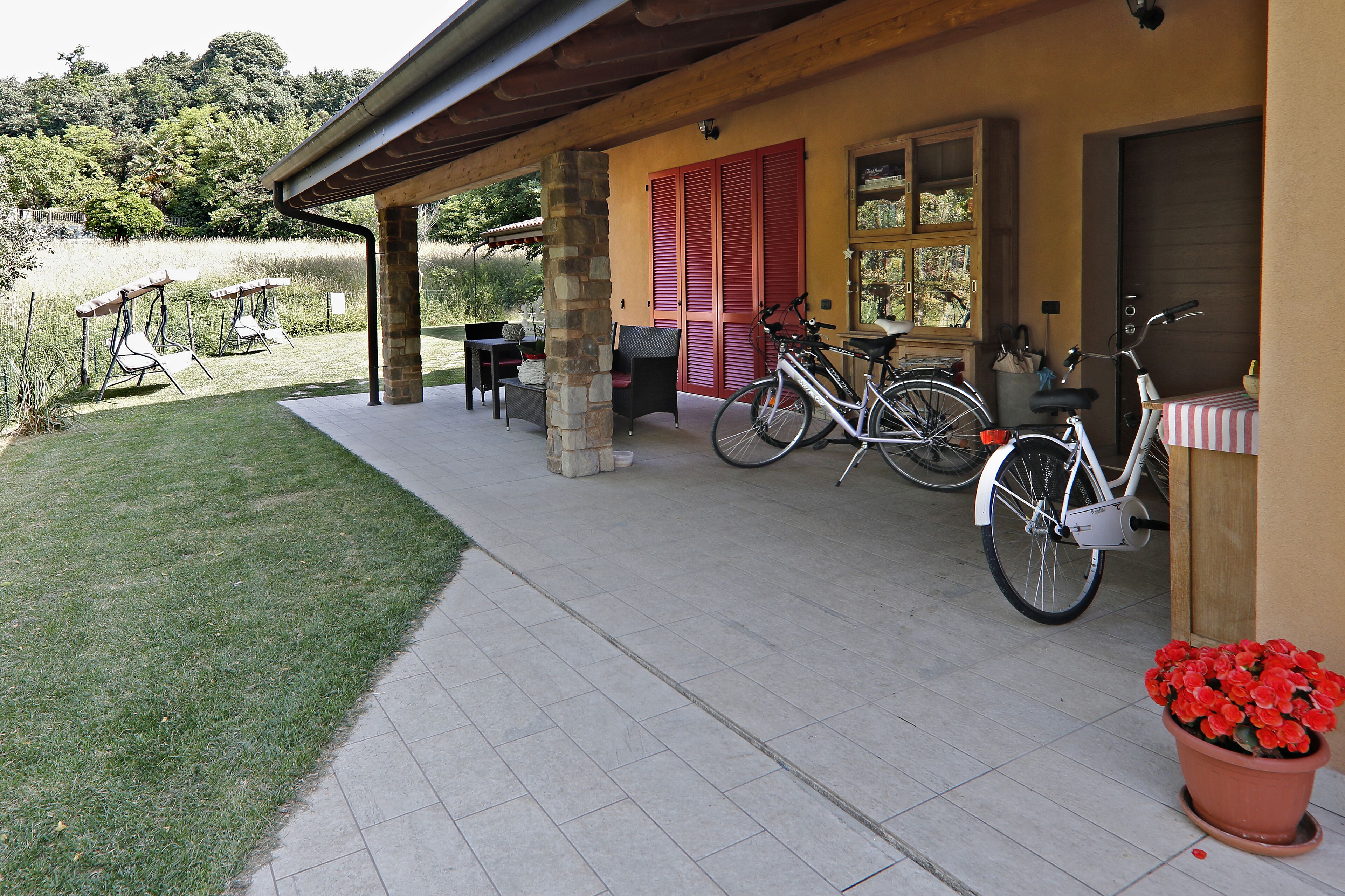 A covered patio area with outdoor seating, a bicycle, and a potted plant.