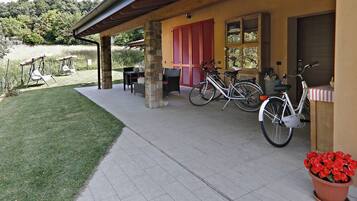 A covered patio area with outdoor seating, a bicycle, and a potted plant.