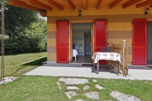 A building with red shutters, a table with a white tablecloth, and a wooden fence. - Agriturismo Terra e Lago d'Iseo (Paratico)